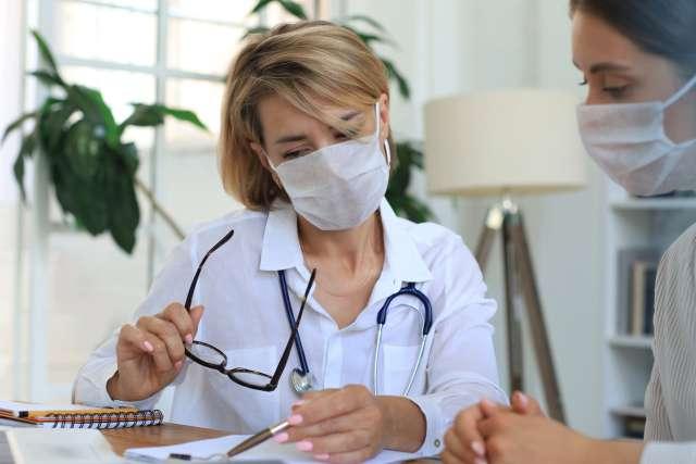 Doctor therapist in medical mask on consultation with patient in office.