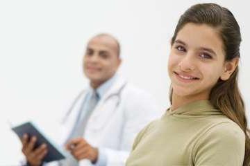 Girl smiling sitting next to doctor