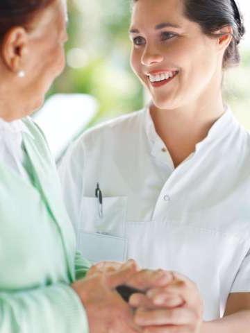 Female nurse comforting older female patient